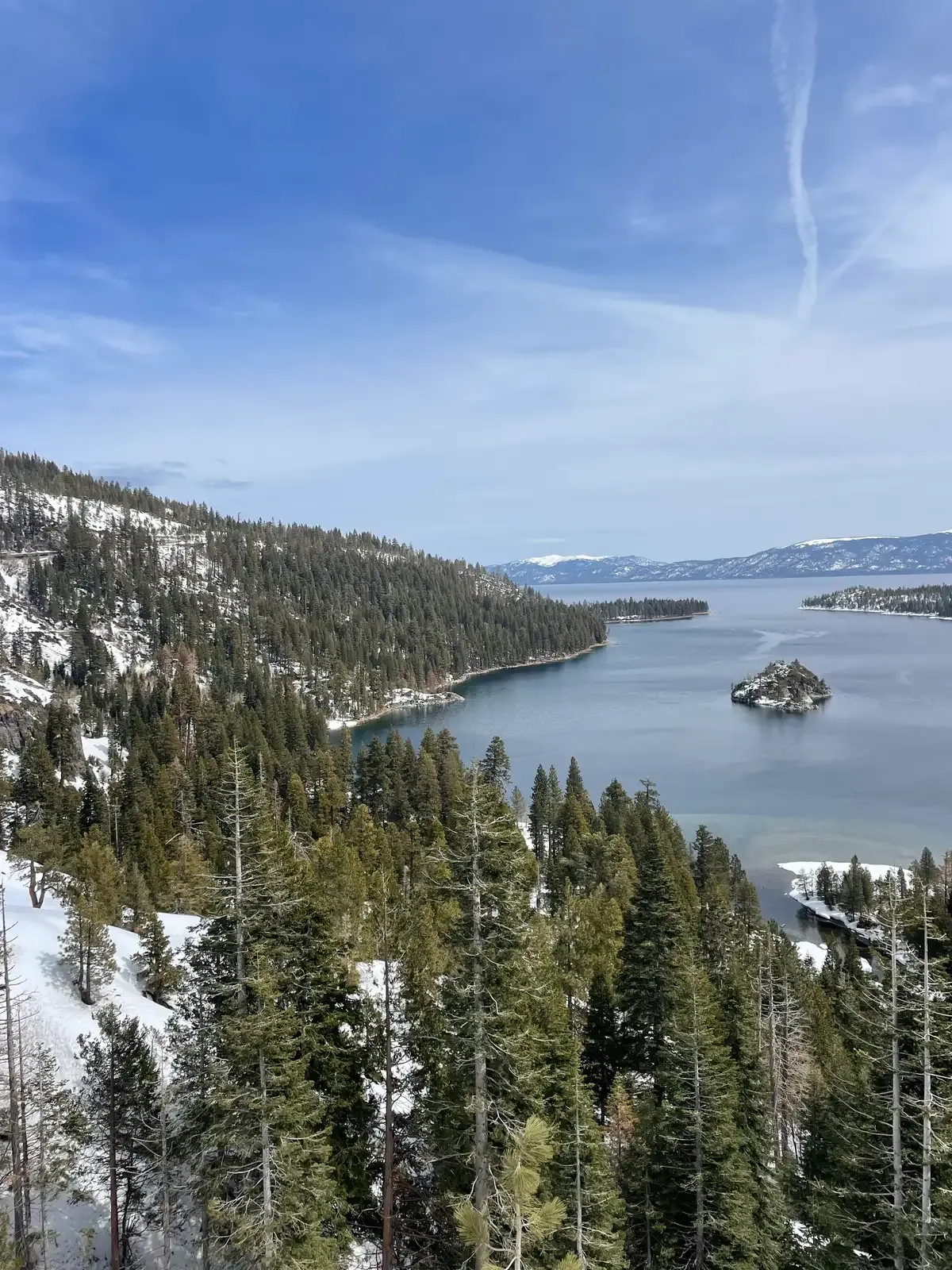 Emerald Bay seen down a snowy forested slope with Fannette Island and the lake beyond